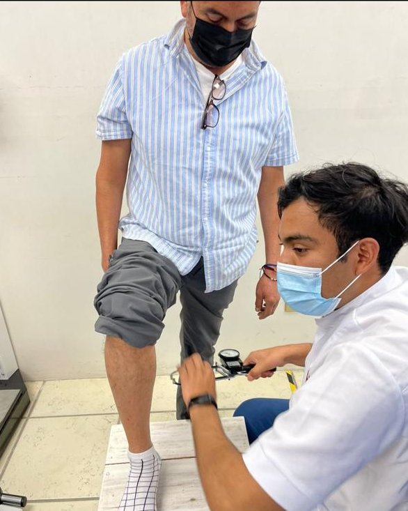 Jesús David mide el pliegue de la pantorrilla con un plicómetro, con la pierna del paciente apoyada en un escalón