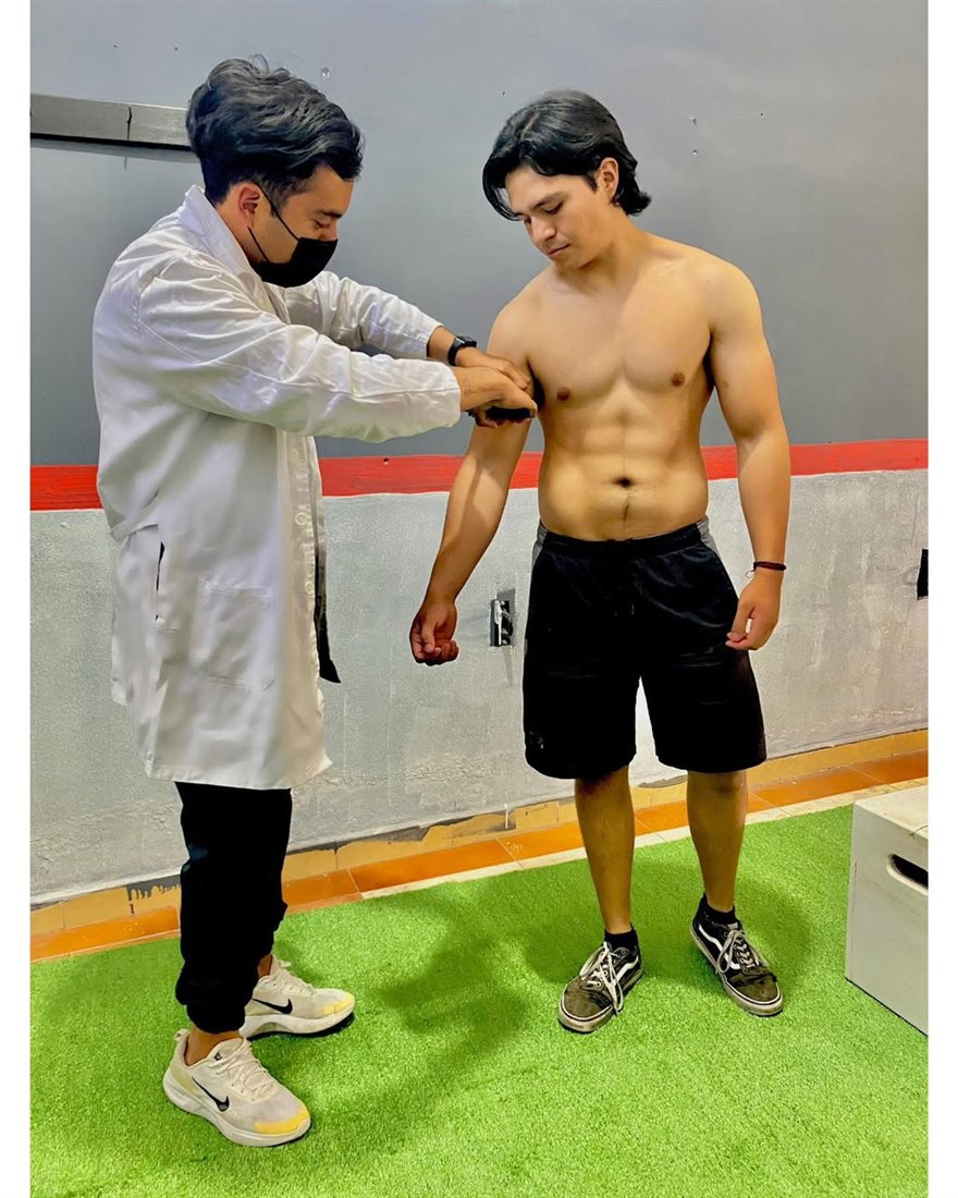 Jesús David toma el pliegue del tríceps con un plicómetro a un paciente con el brazo relajado